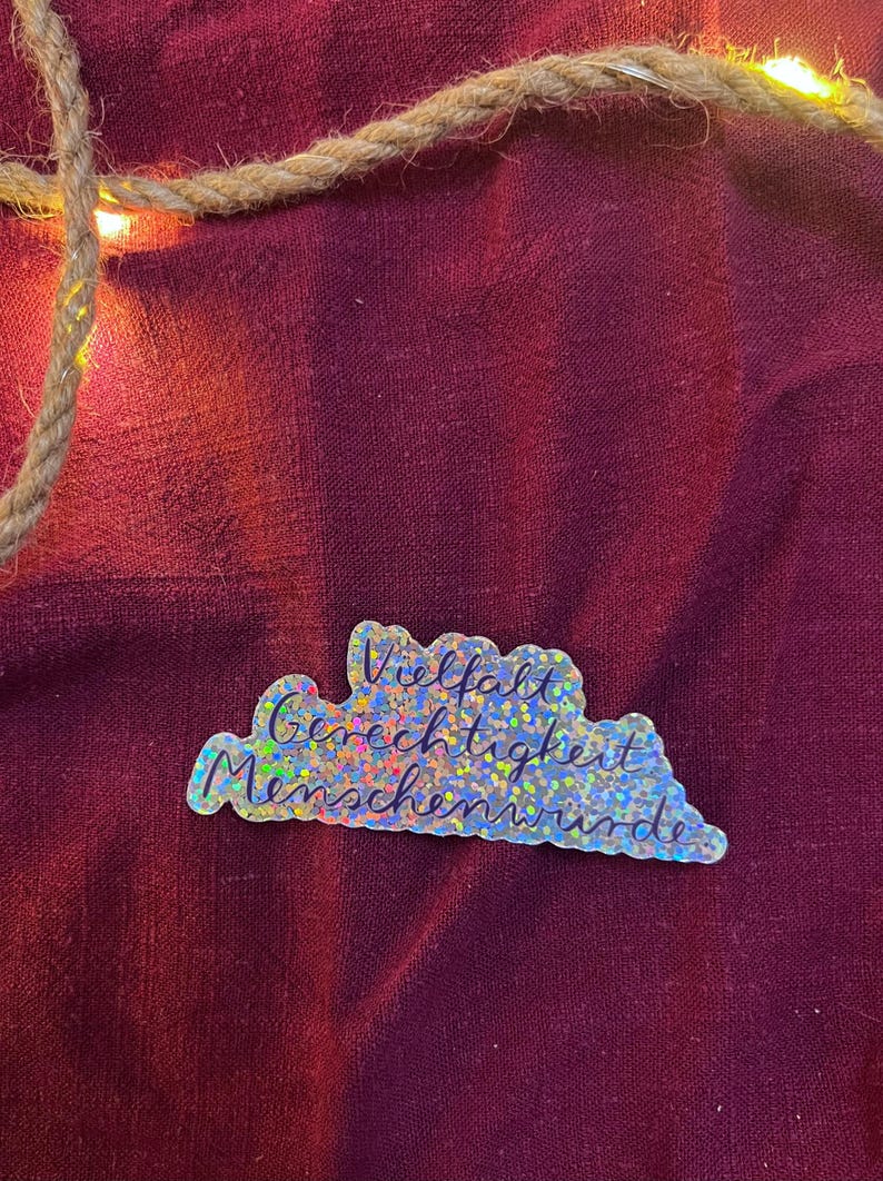 Sticker „Vielfalt. Gerechtigkeit. Menschenwürde.“ | Ein hochwertiger Sticker mit Glitzereffekt - zur Personalisierung von Handy, Laptop, …