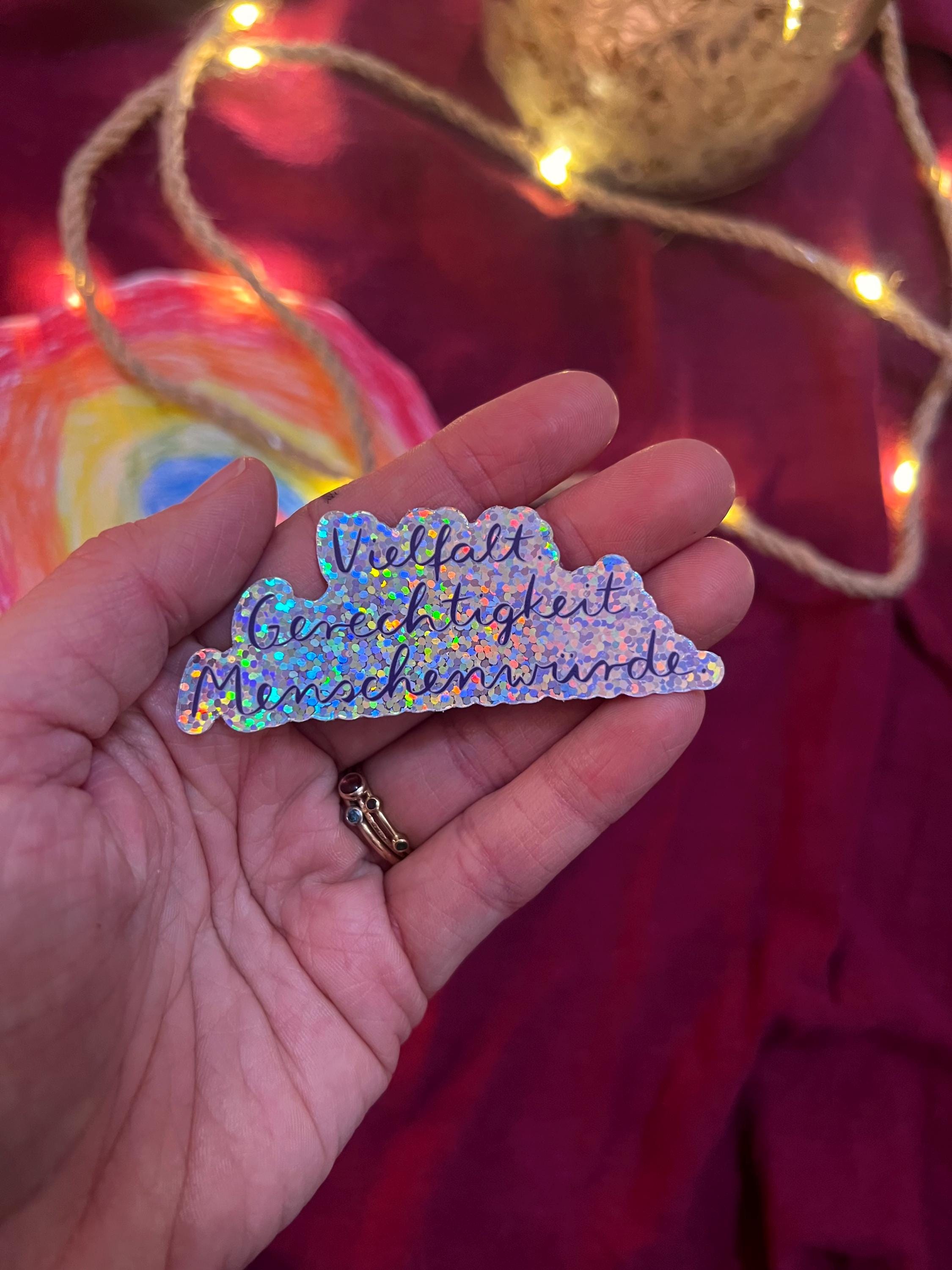 Sticker „Vielfalt. Gerechtigkeit. Menschenwürde.“ | Ein hochwertiger Sticker mit Glitzereffekt - zur Personalisierung von Handy, Laptop, …